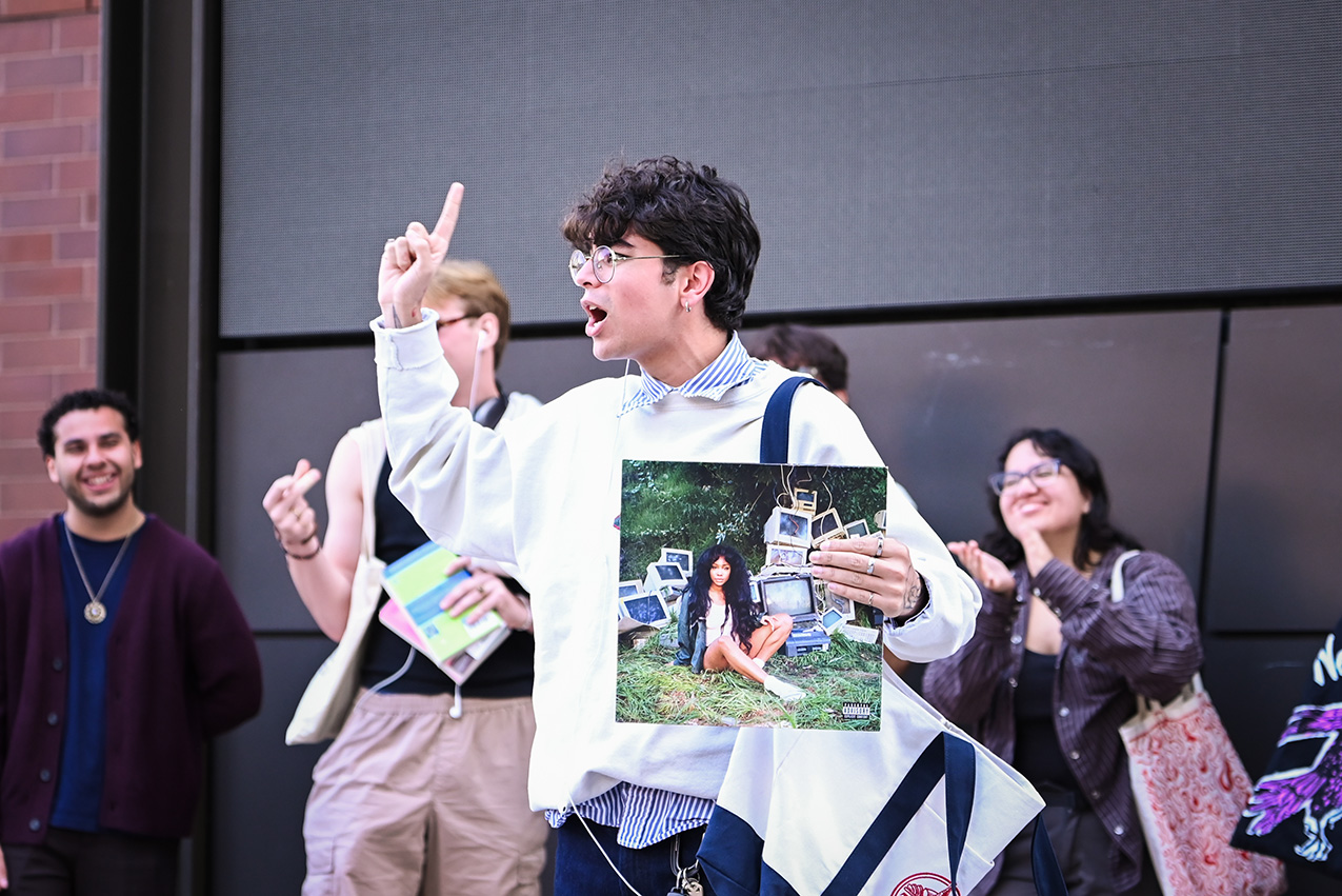Photo of a young man speaking loudly with a SZA album in hand.