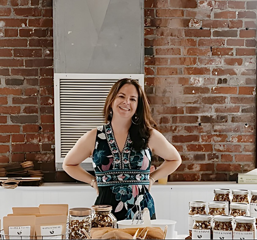 Photo of Amanda Smallwood standing behind    a table with her granola on it.
