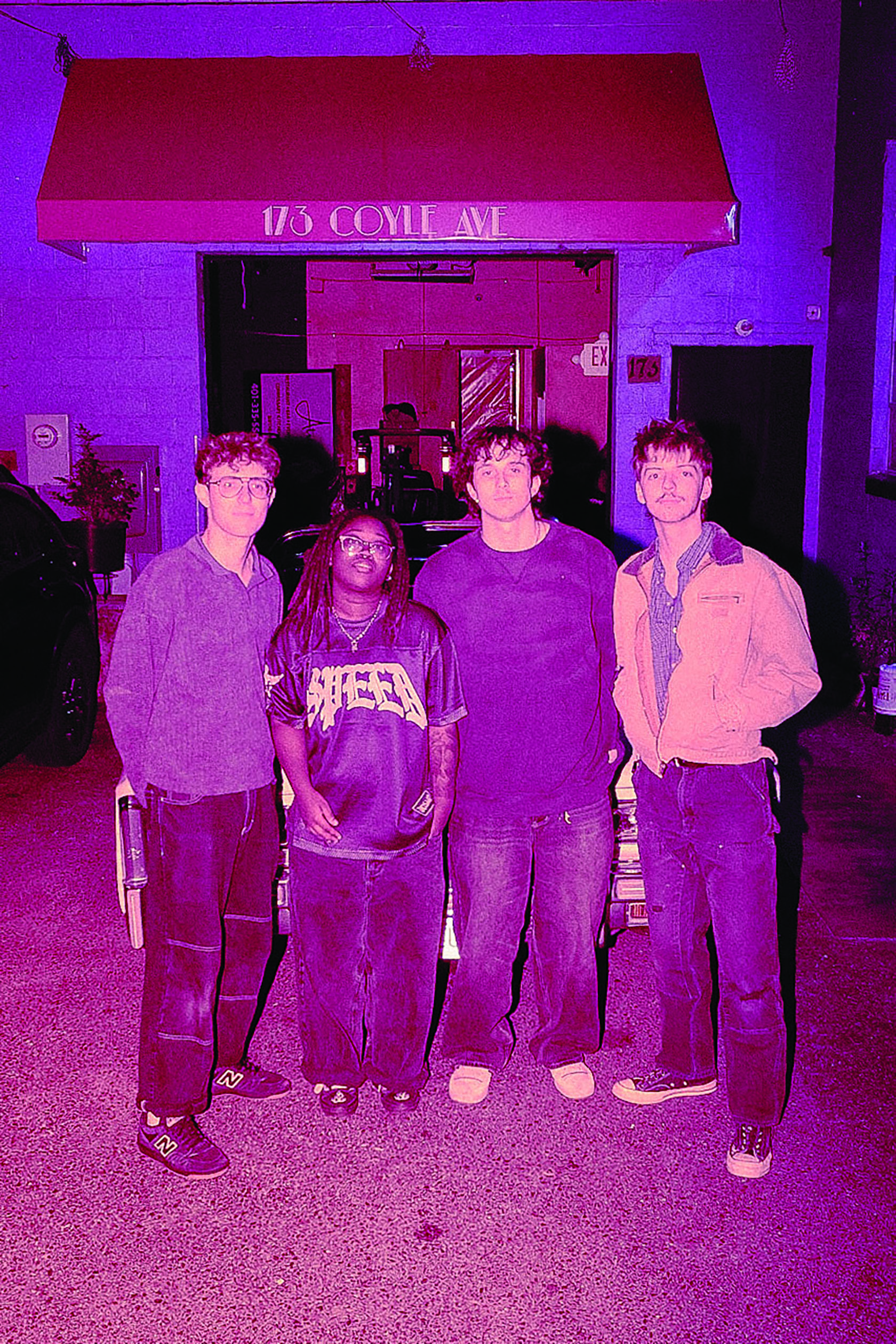 Four bandmates standing in front of an old car