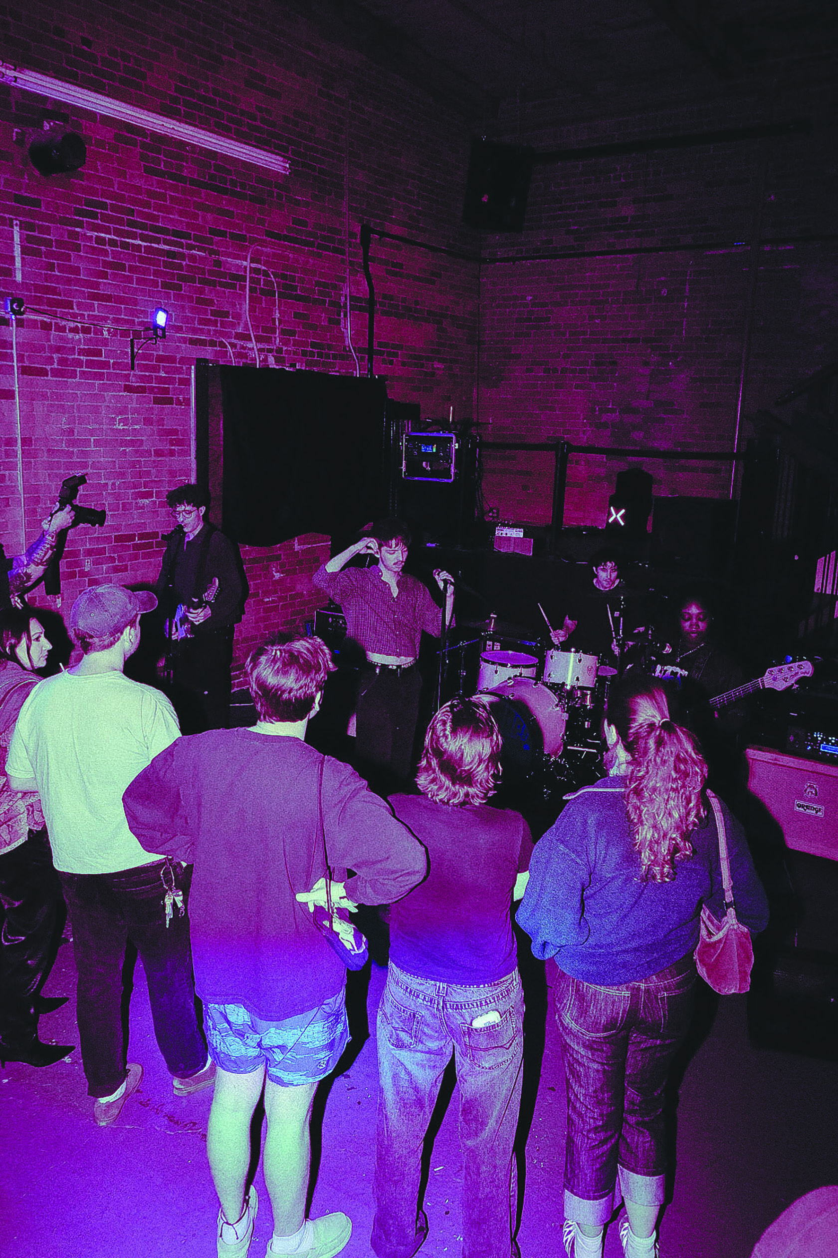 A crowd of four people standing in front of four bandmemebers getting ready to play their next song