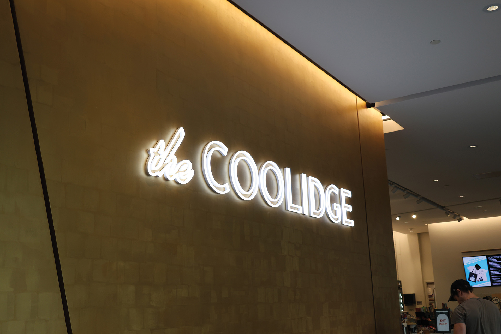 Photo of a sign that says the Coolidge with illuminated letters against a yellow wall