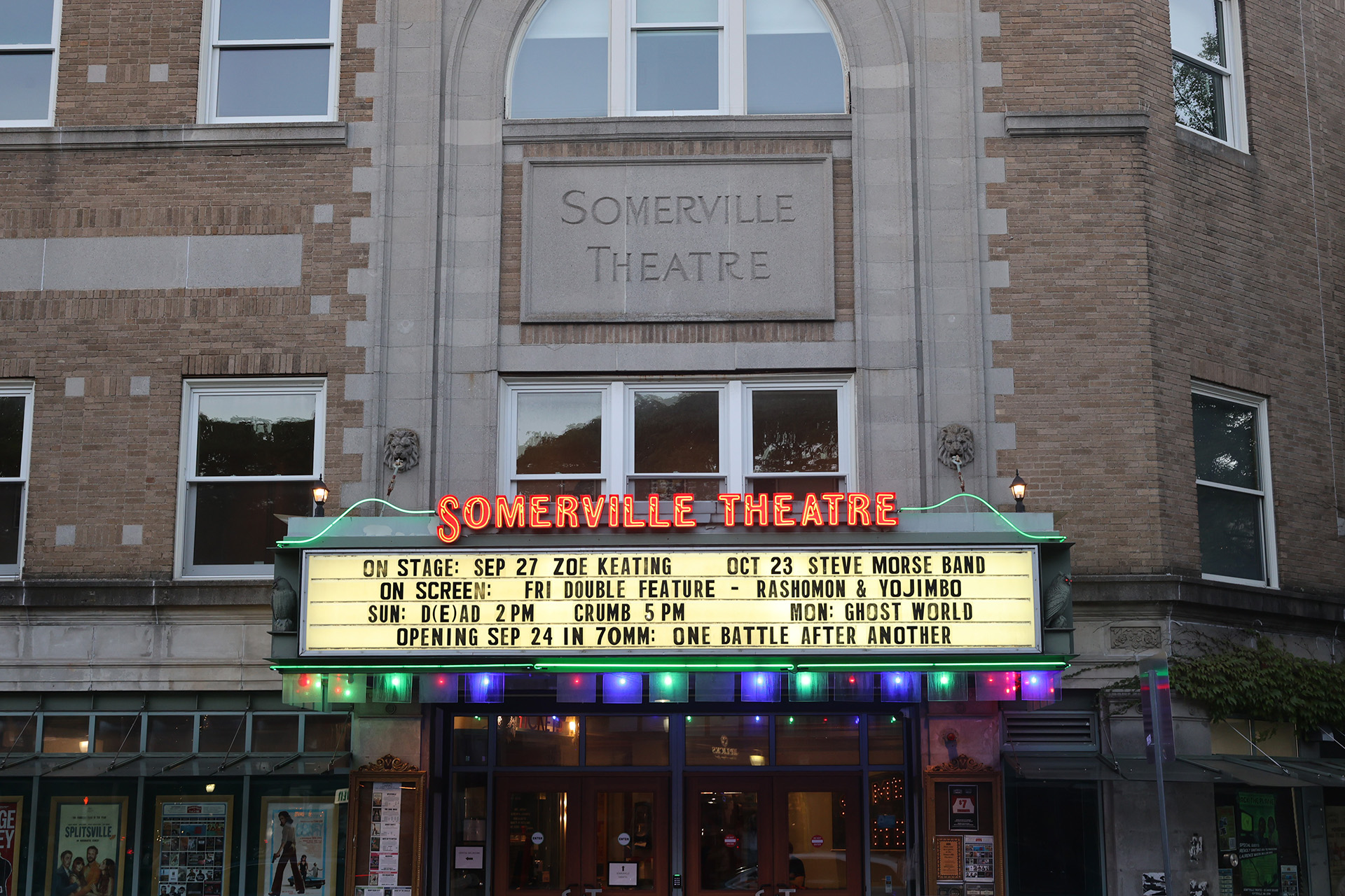 Photo shows the illuminated marquee and entrance of the historic Somerville Theater in Davis Square