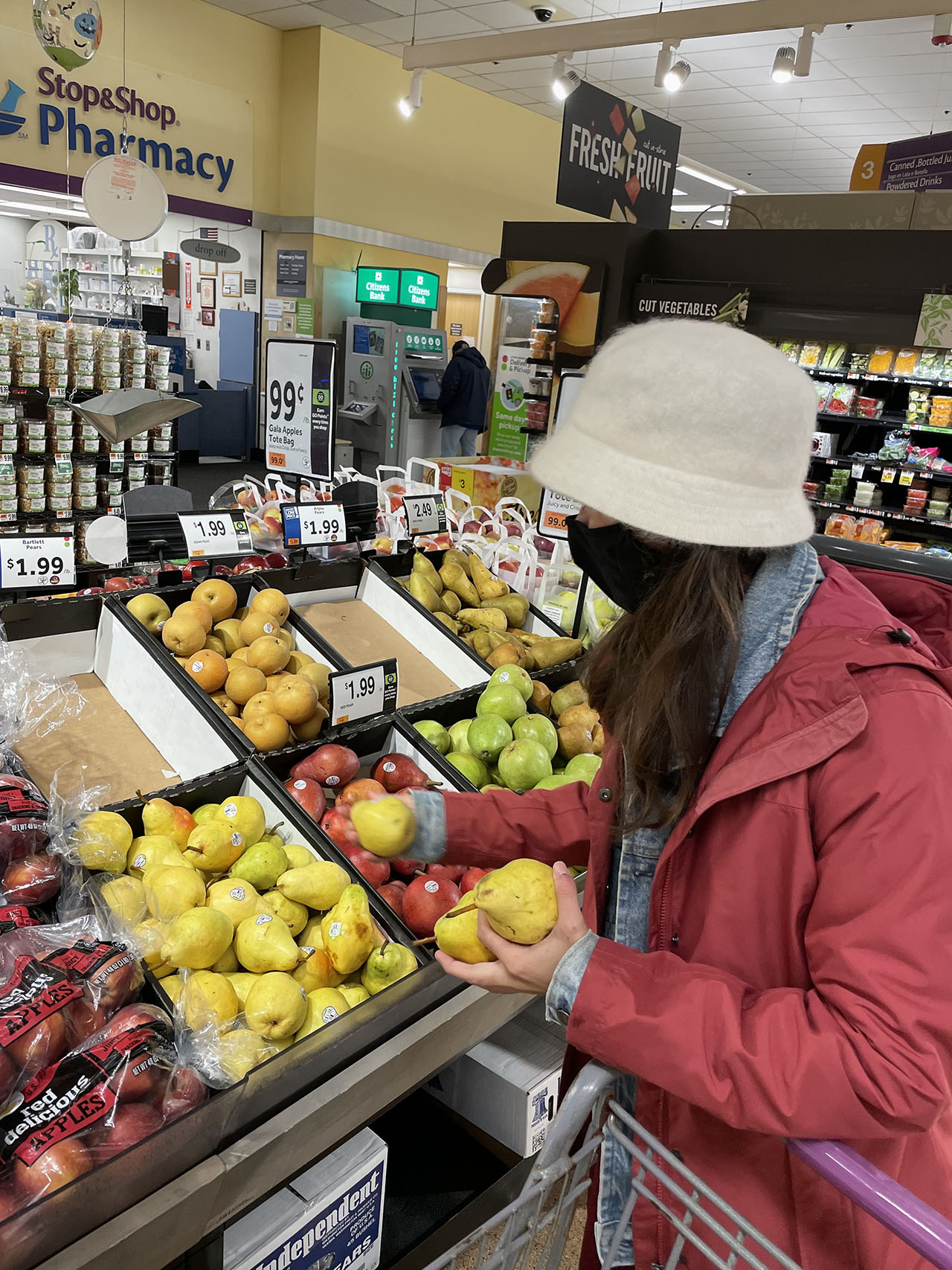Savanna Nolau, in a bright red coat, grabbing a few yellow pears during a shopping trip with Instacart
