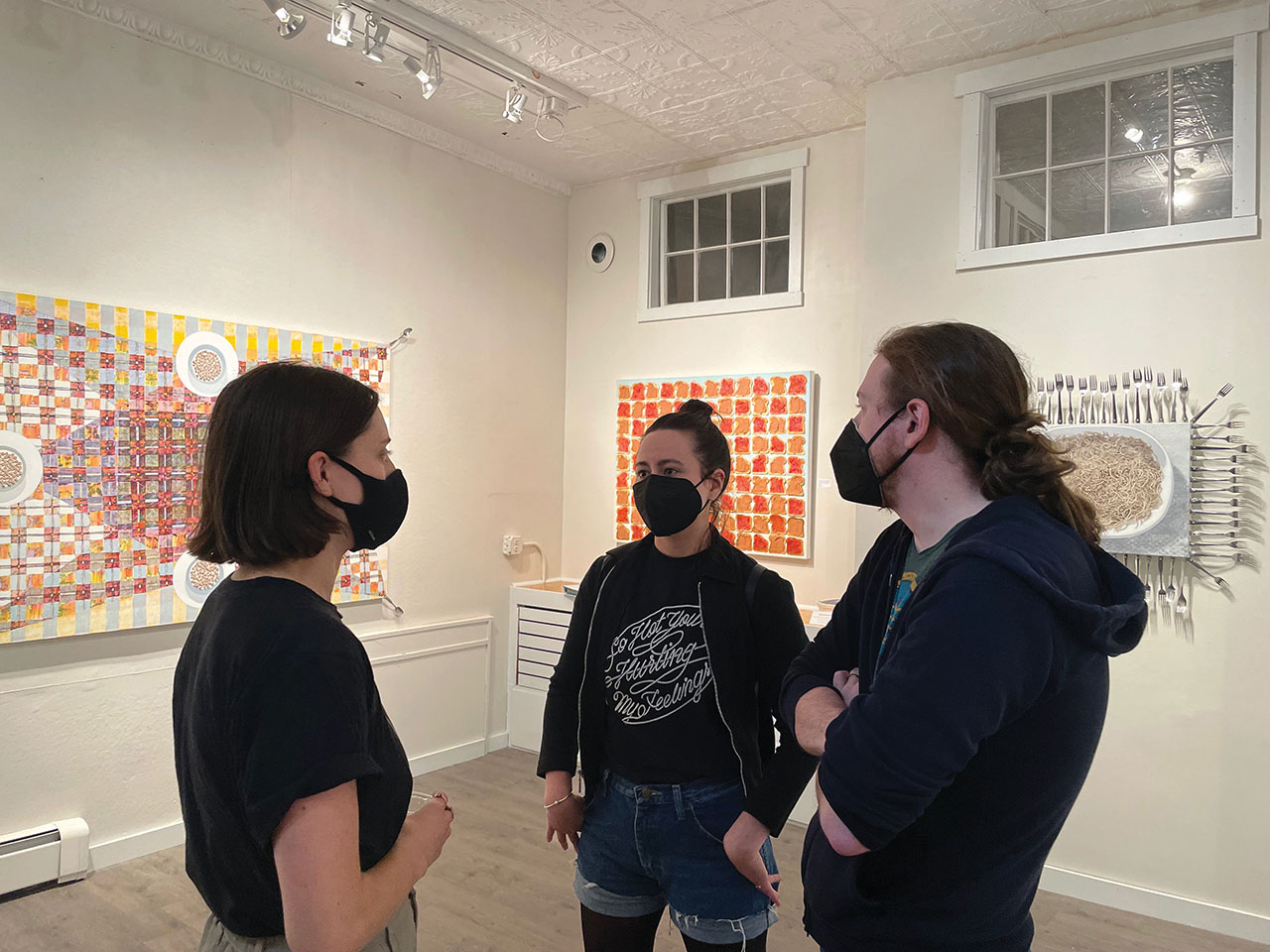Three people talking in gallery