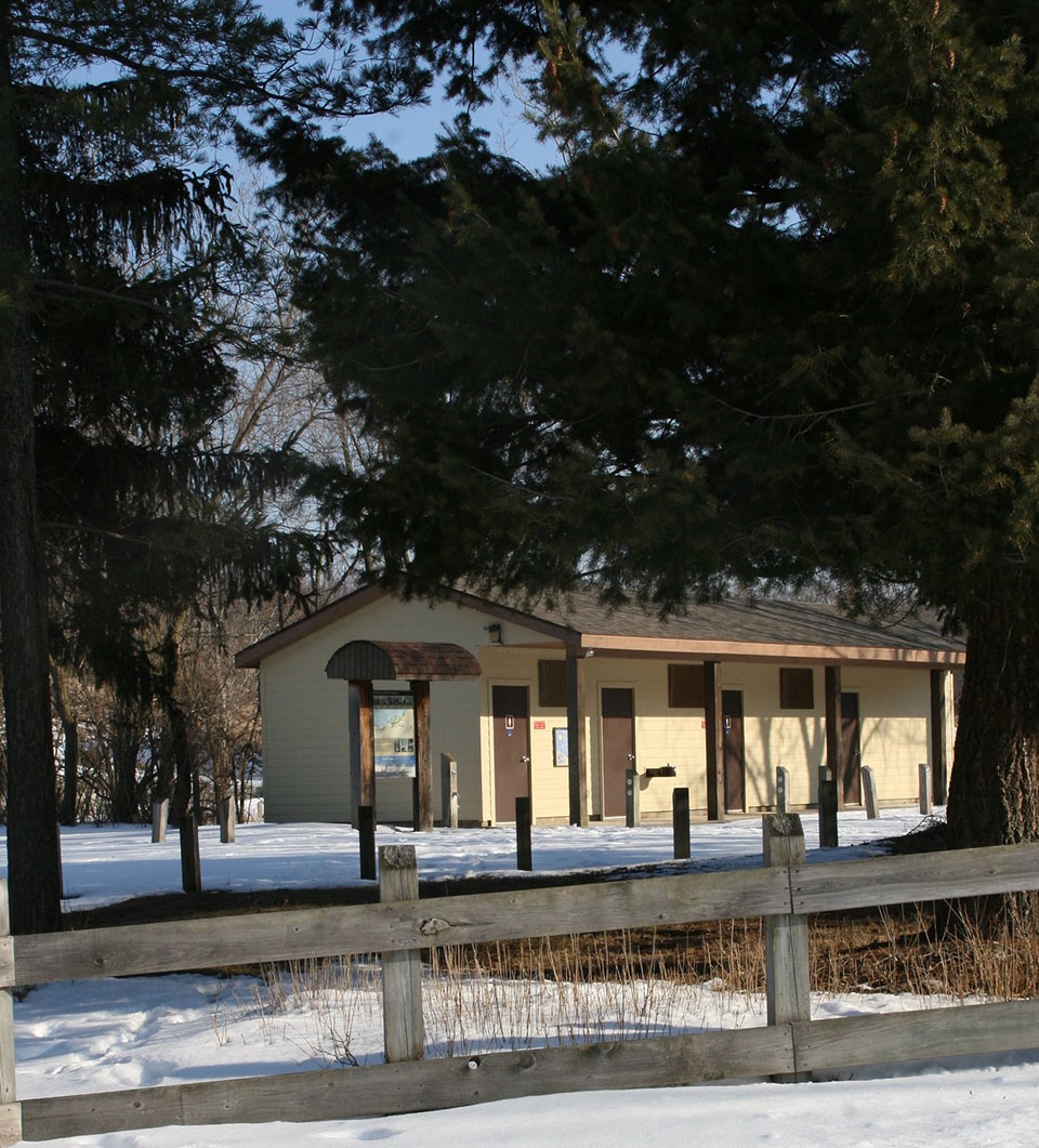 A yellow and brown restroom facility stands in the middle of the trees at Indiana Dunes National Park.