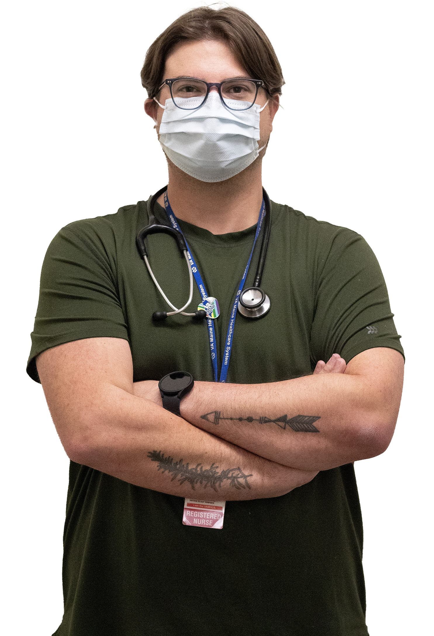 pictured: Nick Durand, a nurse, is  staring at the camera wearing a stethescope around his neck and a mask over his face. He has tattoos on his forearms