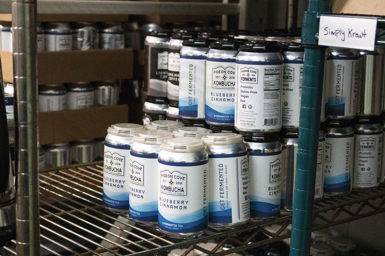 Cans of blueberry cinnamon flavored kombucha sit on a shelf packaged.