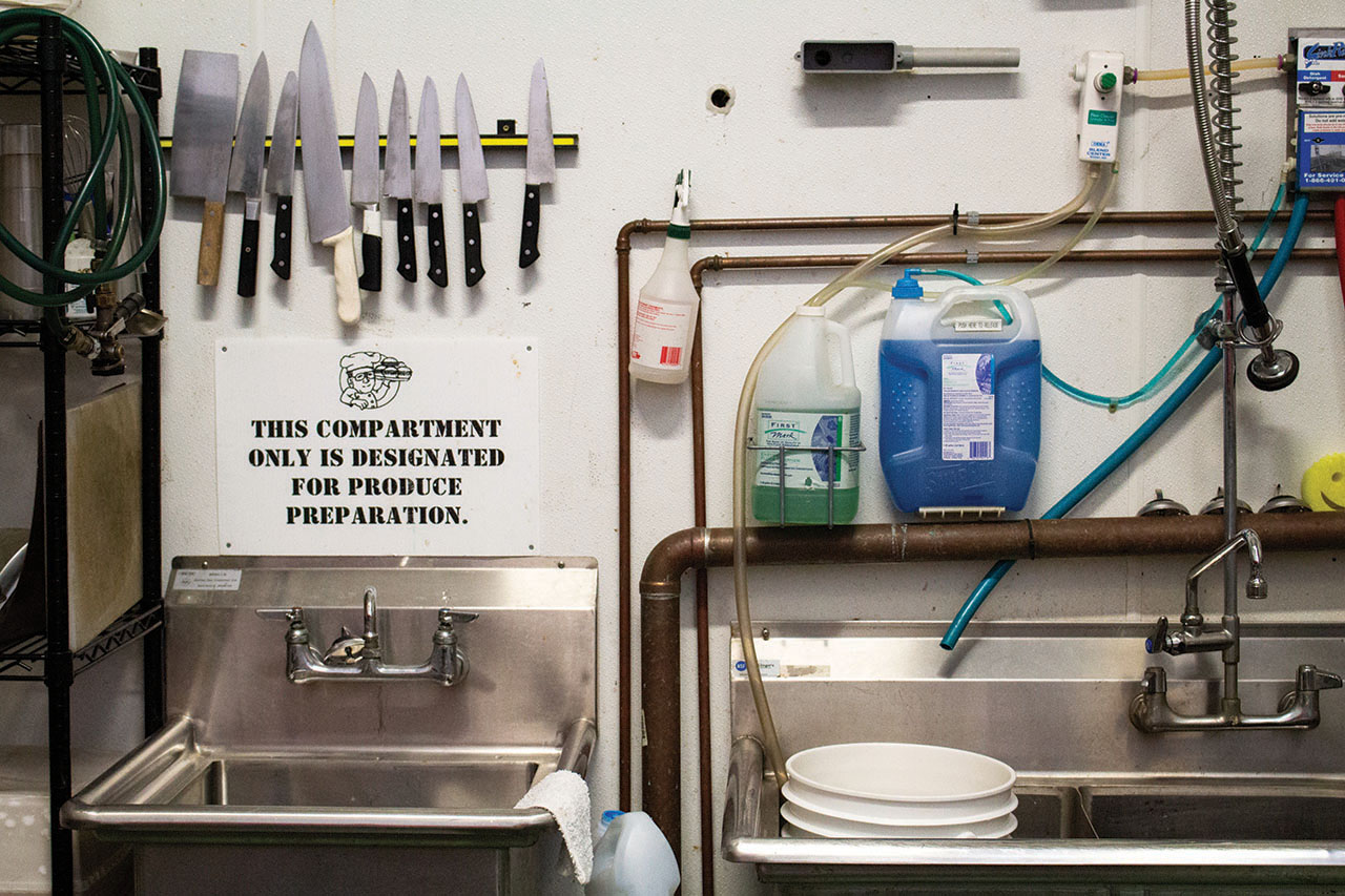 The kitchen preparation area in Pigeon Cove Ferments has knives, a sink, and cleaning equipment